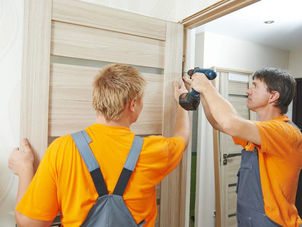 A handyman fixing a door in a new homeowner's house