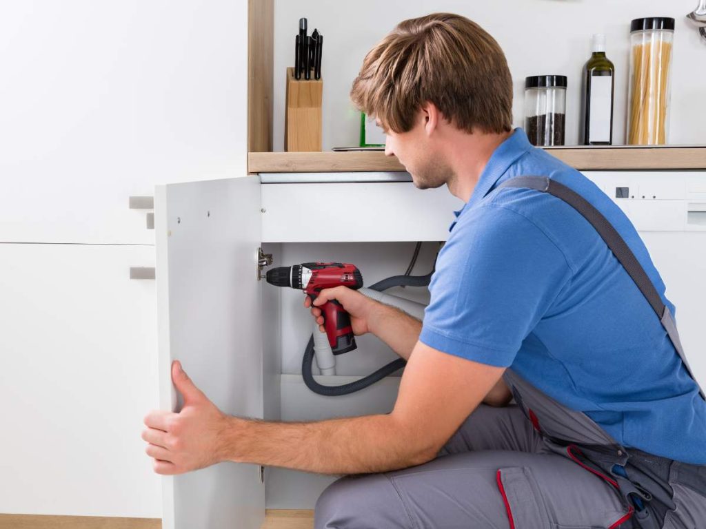 A handyman fixing a kitchen cabinet to increase a home's value