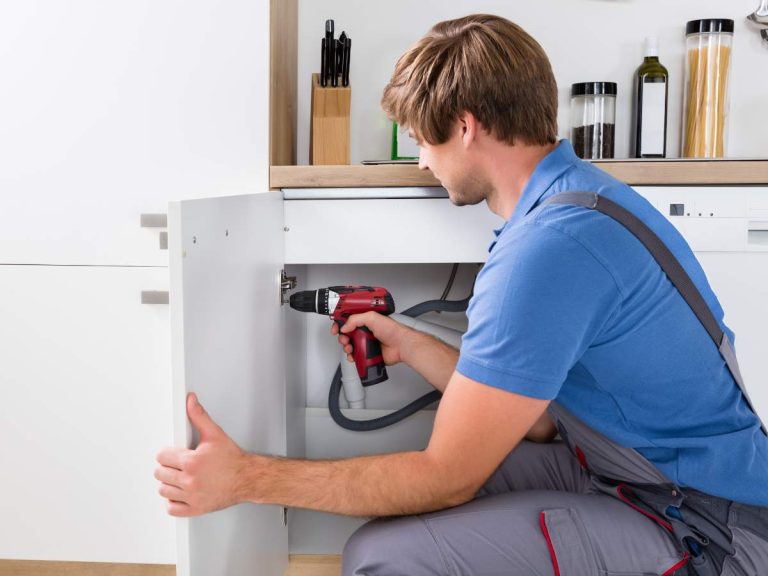 A handyman fixing a kitchen cabinet to increase a home's value