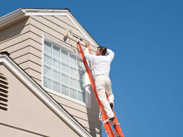 Handyman painting the exterior of a house to improve curb appeal