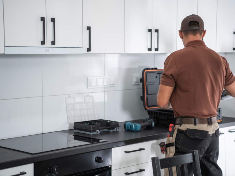 A handyman installing safety locks on cabinets to baby-proof a home